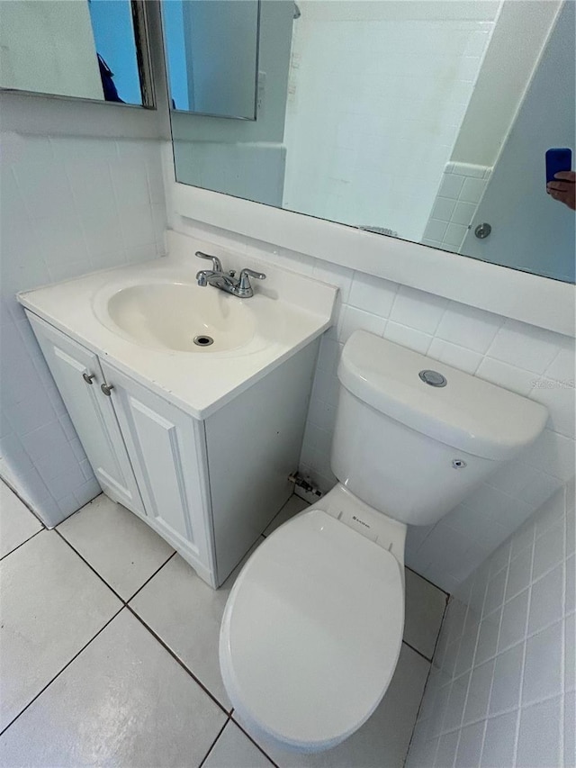 bathroom featuring tile patterned floors, tile walls, toilet, and vanity