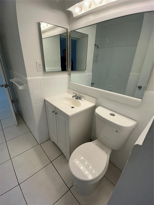 bathroom with toilet, vanity, tile patterned floors, and tile walls