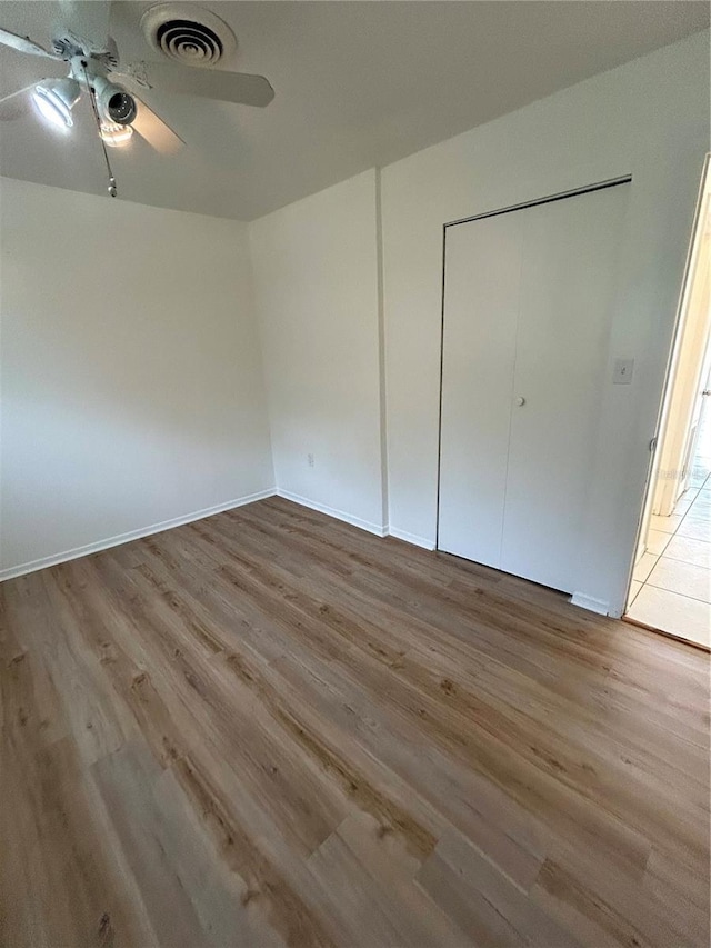 unfurnished bedroom featuring ceiling fan, a closet, and light wood-type flooring