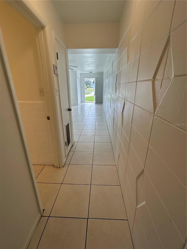 hall featuring tile walls and light tile patterned floors