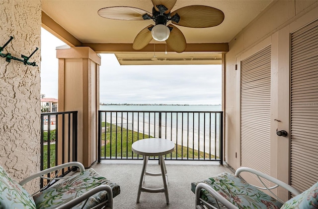 balcony with a water view, a beach view, and ceiling fan