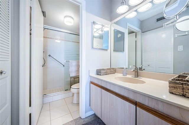 bathroom featuring an enclosed shower, vanity, tile patterned floors, and toilet