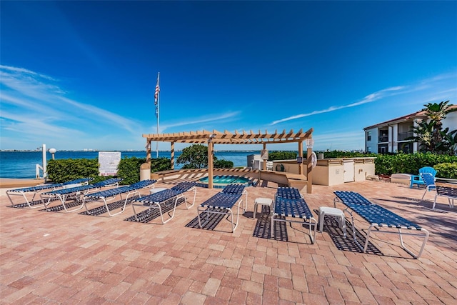 view of patio / terrace featuring a pergola, exterior kitchen, and a water view