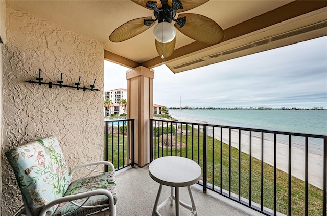 balcony with a water view, ceiling fan, and a beach view