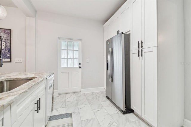 kitchen with light stone counters, stainless steel fridge, dishwasher, and white cabinets