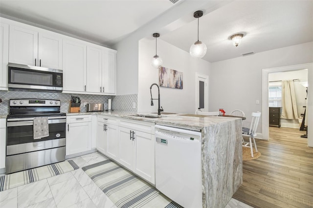 kitchen with appliances with stainless steel finishes, decorative light fixtures, white cabinets, kitchen peninsula, and light stone countertops