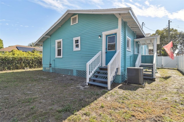 back of house with cooling unit and a yard