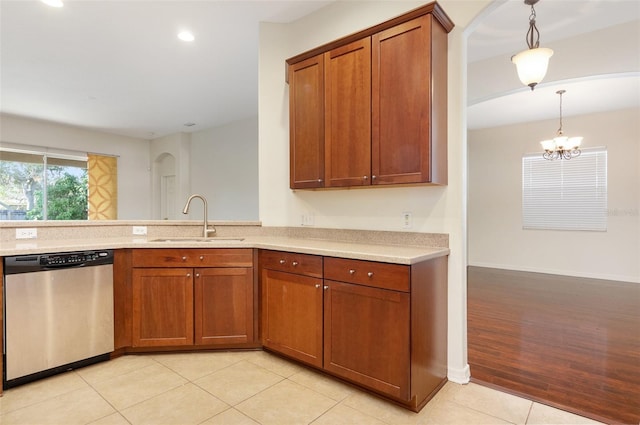 kitchen featuring a notable chandelier, hanging light fixtures, light tile patterned floors, stainless steel dishwasher, and sink