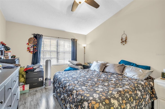 bedroom featuring ceiling fan, hardwood / wood-style floors, lofted ceiling, and a textured ceiling