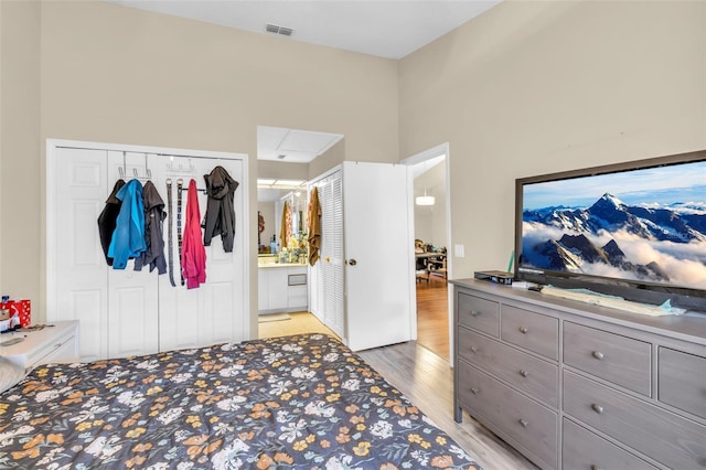 bedroom featuring a closet, light hardwood / wood-style floors, and ensuite bath