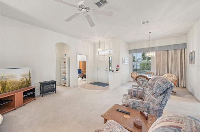 carpeted living room featuring ceiling fan with notable chandelier