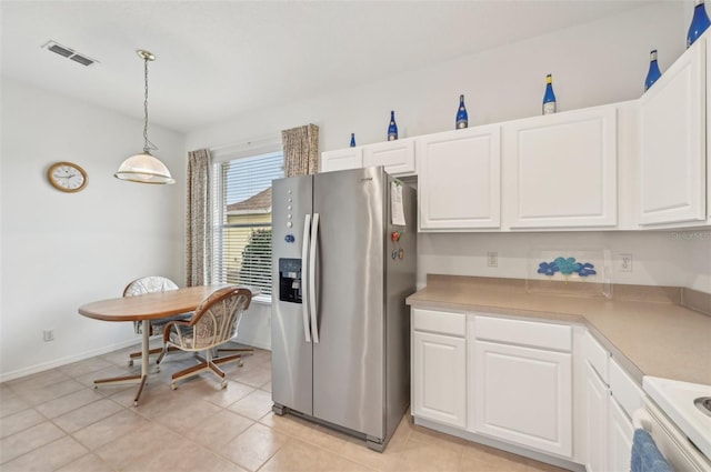 kitchen with white cabinets, range, hanging light fixtures, stainless steel fridge, and light tile patterned flooring