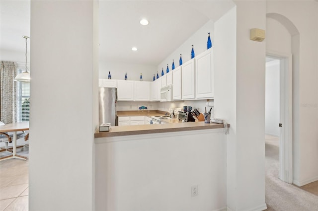 kitchen featuring white appliances, white cabinetry, light carpet, hanging light fixtures, and kitchen peninsula