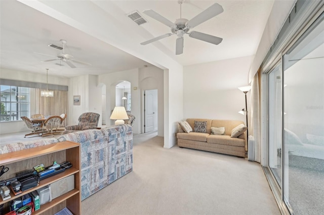 carpeted living room featuring ceiling fan with notable chandelier