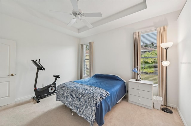 bedroom featuring ceiling fan, a raised ceiling, and light carpet