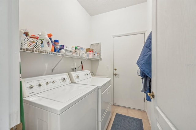 clothes washing area with light tile patterned floors and washer and dryer