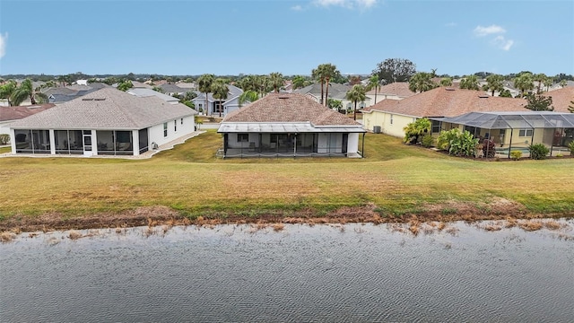 back of property with a water view, a yard, and a sunroom