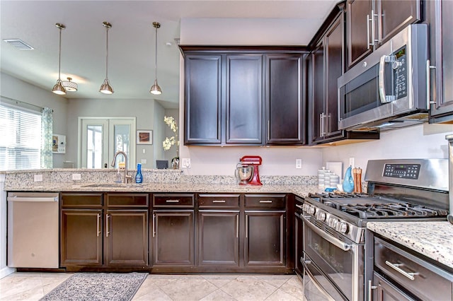 kitchen with dark brown cabinetry, sink, light stone counters, pendant lighting, and stainless steel appliances