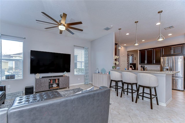 living room featuring ceiling fan, light tile patterned flooring, and a textured ceiling