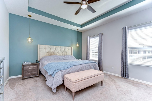 bedroom featuring light carpet, ceiling fan, and a tray ceiling