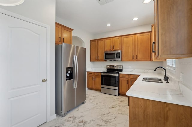 kitchen featuring appliances with stainless steel finishes, light stone countertops, and sink