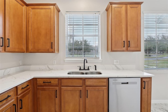 kitchen featuring sink, stainless steel dishwasher, and light stone counters