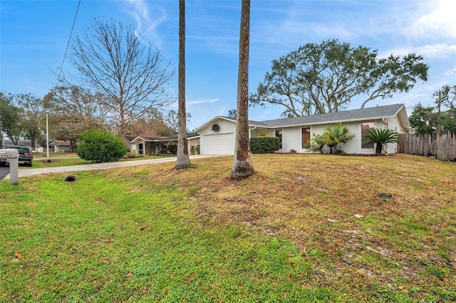 view of front facade with concrete driveway, an attached garage, fence, and a front yard