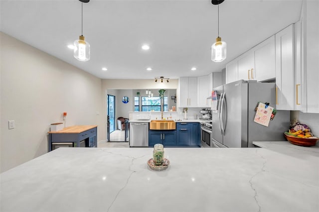 kitchen featuring stainless steel appliances, blue cabinets, decorative light fixtures, and white cabinets