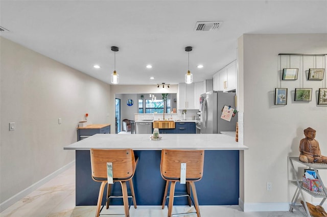 kitchen with appliances with stainless steel finishes, decorative light fixtures, white cabinets, a kitchen breakfast bar, and kitchen peninsula