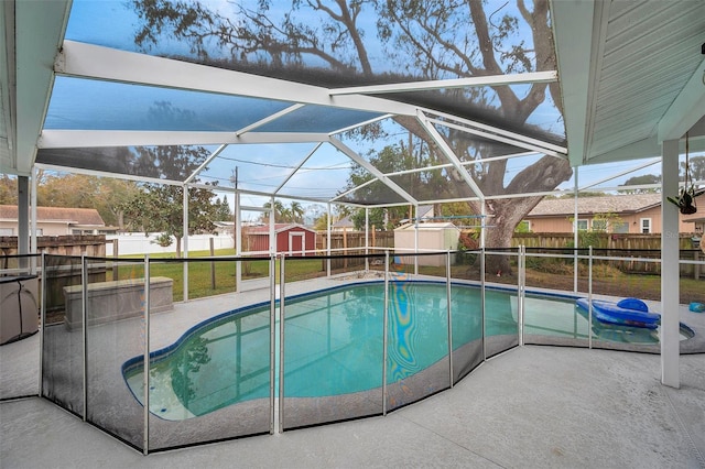 view of swimming pool featuring a patio, a lawn, glass enclosure, and a storage unit