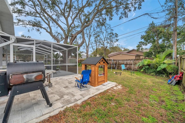 view of yard featuring a patio, a playground, and glass enclosure