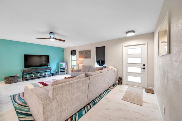 living area with ceiling fan, marble finish floor, and baseboards