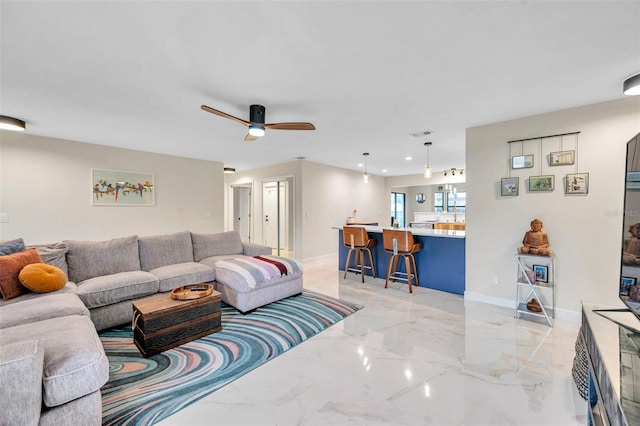 living area featuring a ceiling fan, marble finish floor, and baseboards