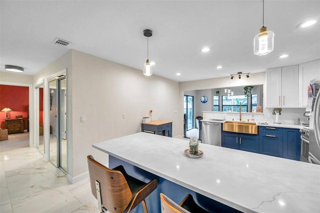 kitchen featuring visible vents, a peninsula, marble finish floor, stainless steel dishwasher, and a sink