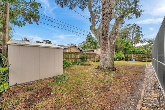 view of yard with a fenced backyard, an outdoor structure, and a storage shed