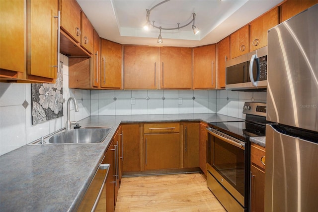 2635 Seville Blvd Unit 109, Clearwater, FL 33764 - kitchen featuring appliances with stainless steel finishes, light hardwood / wood-style floors, sink, rail lighting, and a tray ceiling