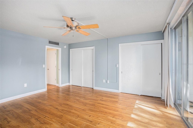 2635 Seville Blvd Unit 109, Clearwater, FL 33764 - unfurnished bedroom with multiple closets, ceiling fan, light wood-type flooring, and a textured ceiling