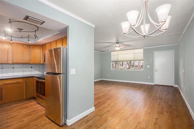 2635 Seville Blvd Unit 109, Clearwater, FL 33764 - kitchen with a textured ceiling, appliances with stainless steel finishes, tasteful backsplash, hanging light fixtures, and light wood-type flooring
