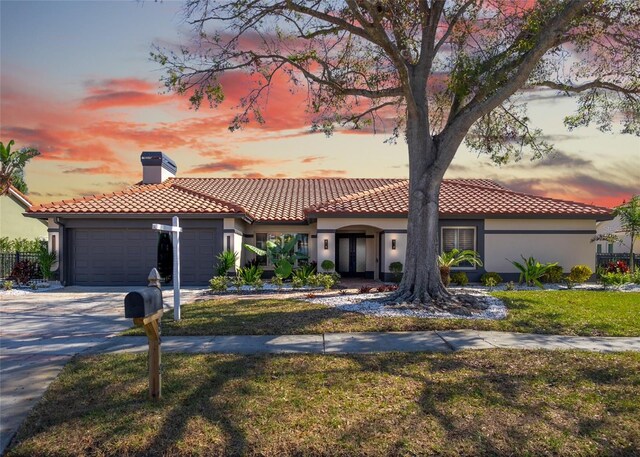 mediterranean / spanish-style home with a yard and a garage