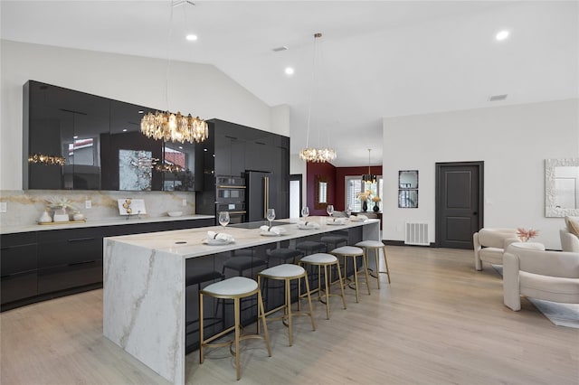 5809 Cruiser Way, Tampa, FL 33615 - kitchen featuring modern cabinets, a chandelier, high vaulted ceiling, double oven, and a breakfast bar area