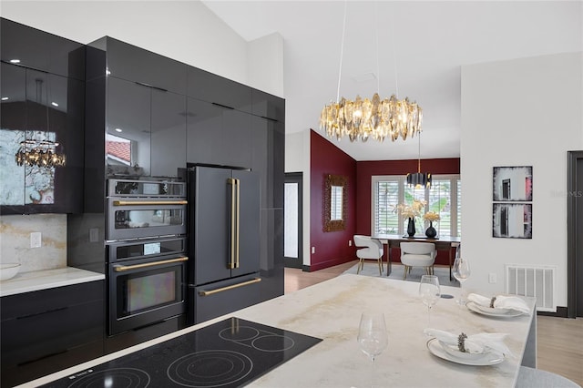 5809 Cruiser Way, Tampa, FL 33615 - kitchen with a chandelier, high end fridge, dark cabinetry, black electric stovetop, and high vaulted ceiling