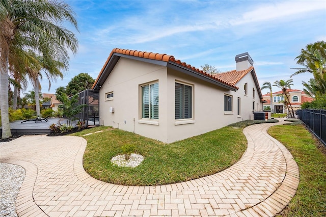5809 Cruiser Way, Tampa, FL 33615 - view of property exterior with stucco siding, a chimney, glass enclosure, a tiled roof, and a patio area