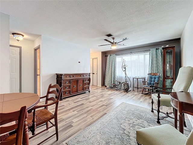 sitting room with ceiling fan, light hardwood / wood-style flooring, and a textured ceiling