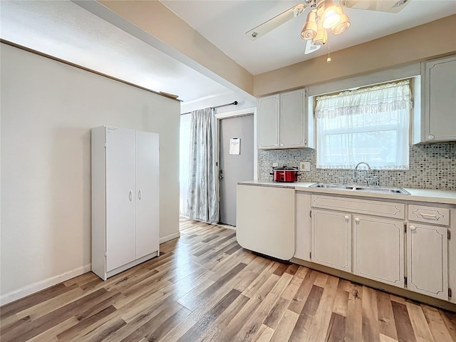 kitchen featuring sink, ceiling fan, dishwasher, decorative backsplash, and light wood-type flooring