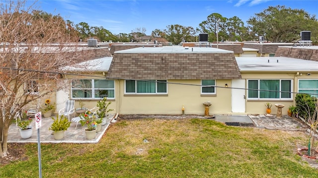 rear view of property with cooling unit, a yard, and a patio area