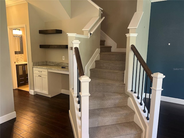 stairs with ornamental molding, built in desk, and hardwood / wood-style floors