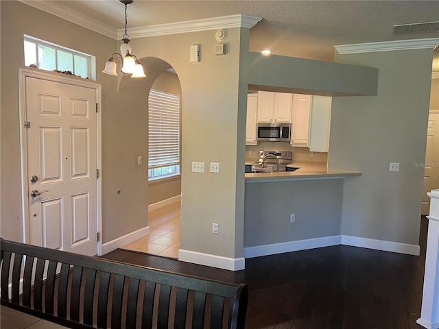 entrance foyer featuring crown molding, sink, light tile patterned floors, and a chandelier