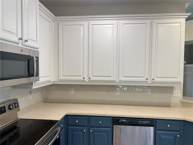 kitchen featuring blue cabinets, appliances with stainless steel finishes, white cabinets, and decorative backsplash