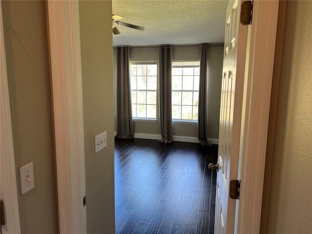 empty room featuring dark hardwood / wood-style flooring, ceiling fan, and a textured ceiling