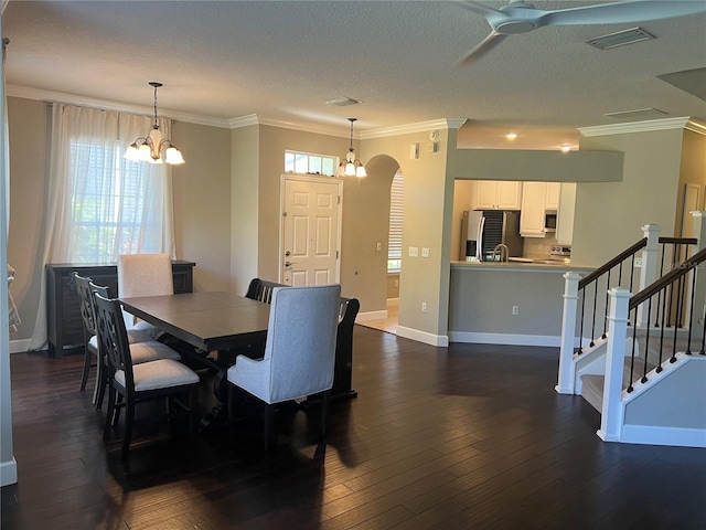 dining space featuring crown molding, ceiling fan with notable chandelier, dark wood-type flooring, and a textured ceiling